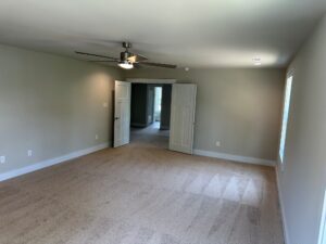 Spacious empty room with beige carpet in Somerset Hill, ceiling fan, double doors, and natural light from window.