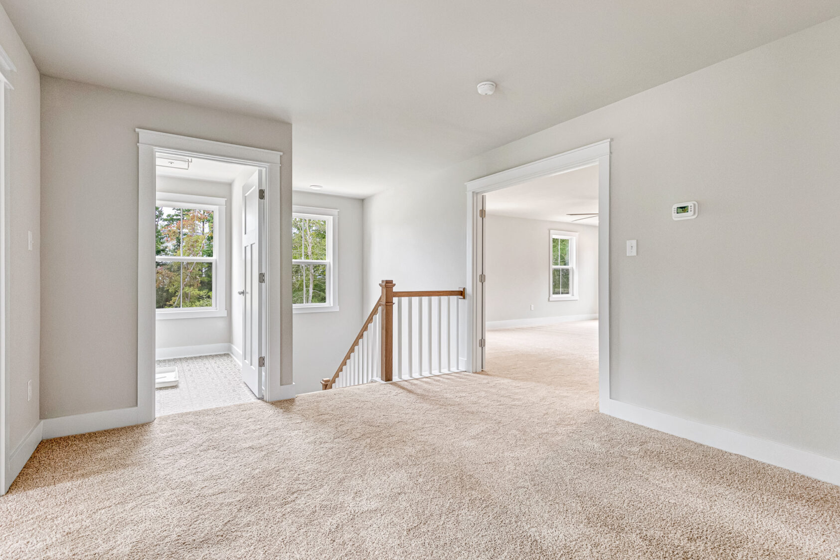 Bright, carpeted upstairs hallway in Lot 20, Somerset Hill, with white walls and open doorway leading to another room.