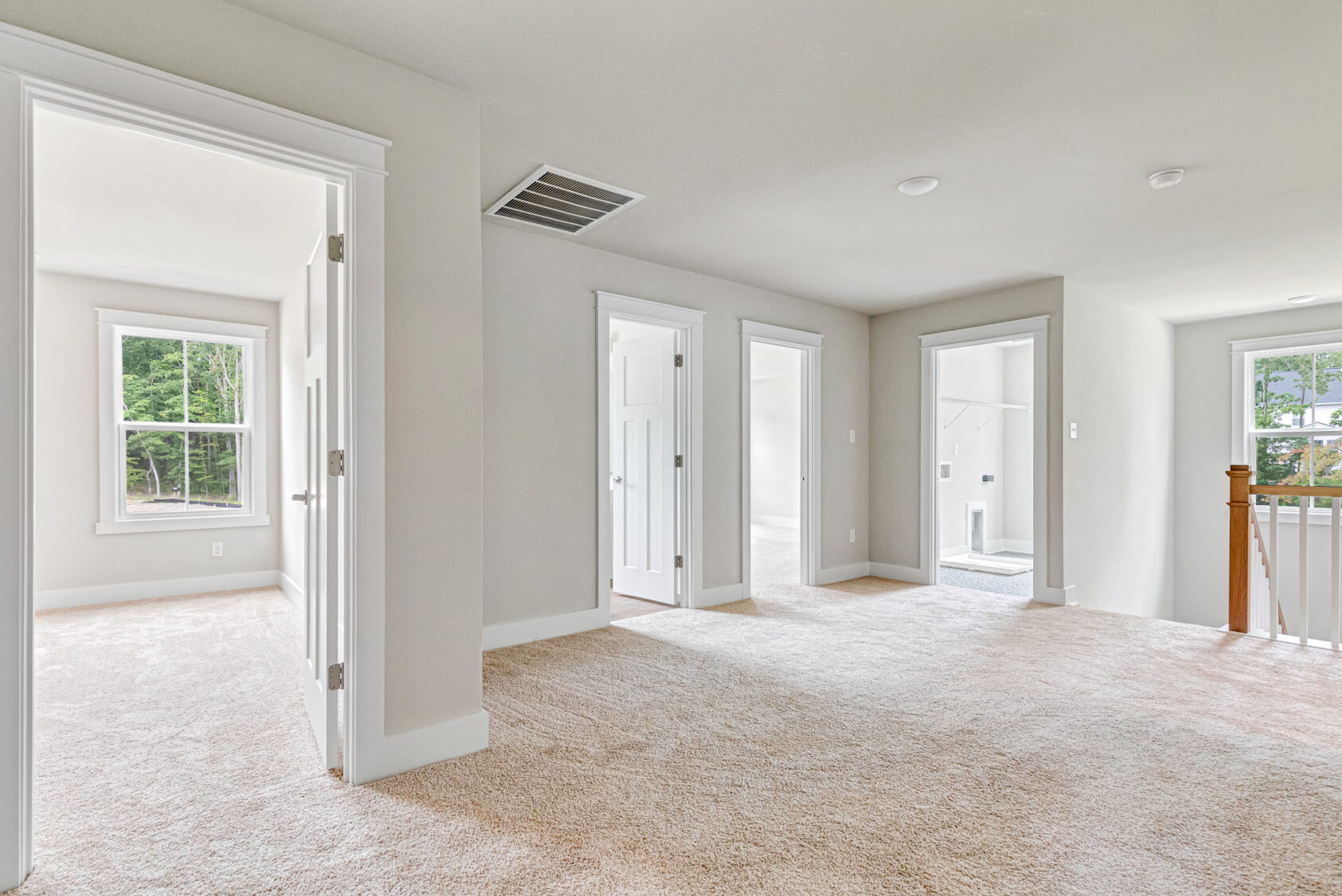 Bright carpeted hallway at Somerset Hill, Lot 20, with white doors and natural light streaming through large windows.