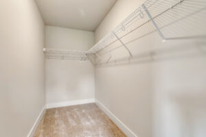 Empty walk-in closet with beige carpet, white walls, and white wire shelving in Somerset Hill’s Lot 20.