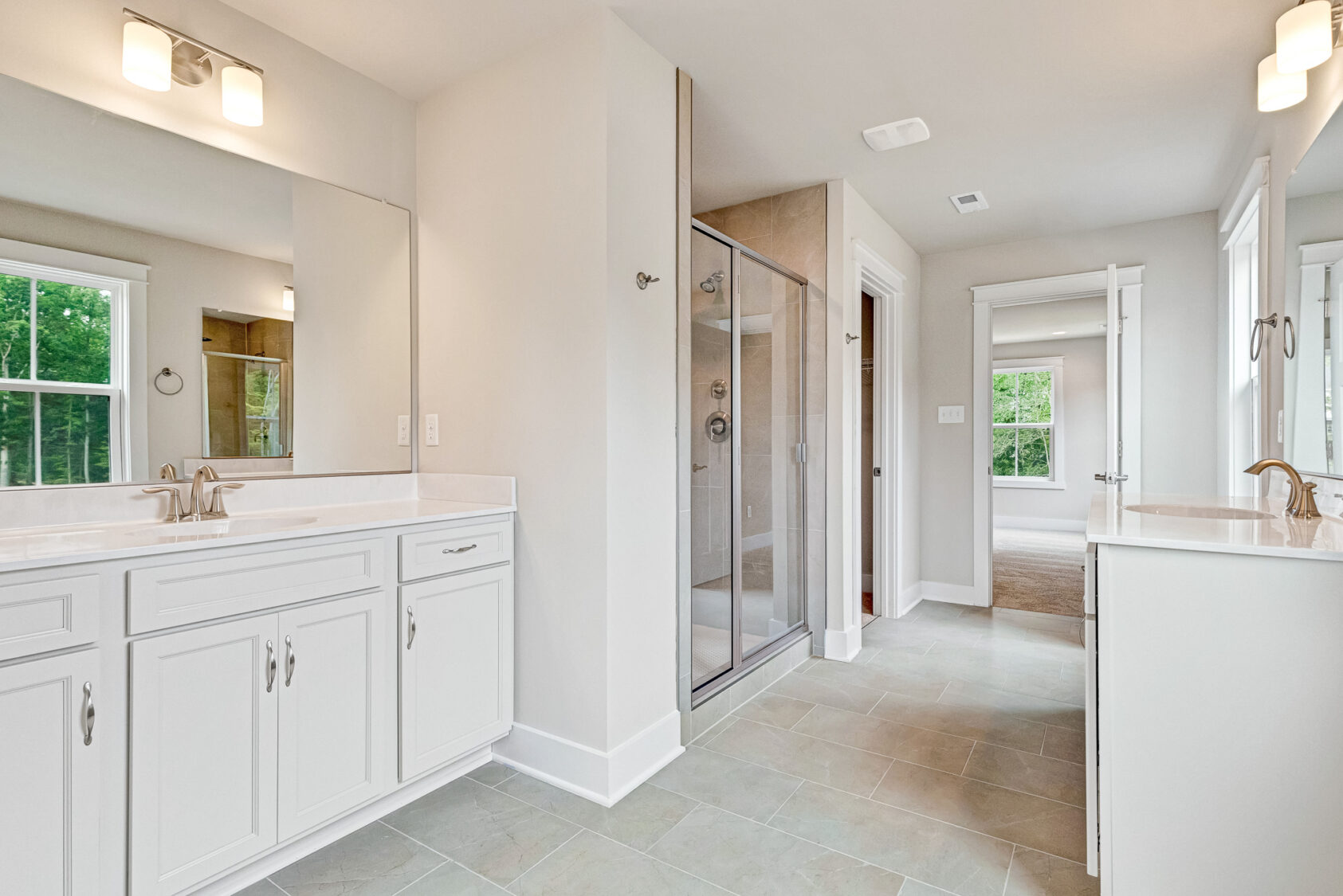 Bright bathroom in Lot 20, Somerset Hill, with double sinks, large mirrors, glass shower, and white cabinets.
