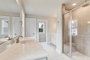 Bright Somerset Hill bathroom with double sinks, marble countertop, glass shower, and two windows on Lot 20.