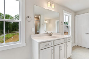 Somerset Hill Lot 20: White bathroom vanity with double sink, large mirror, two lights, and natural light from windows.