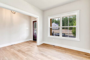 Bright empty room with light wood floors in Somerset Hill, large window, white trim, and glass door leading outside.