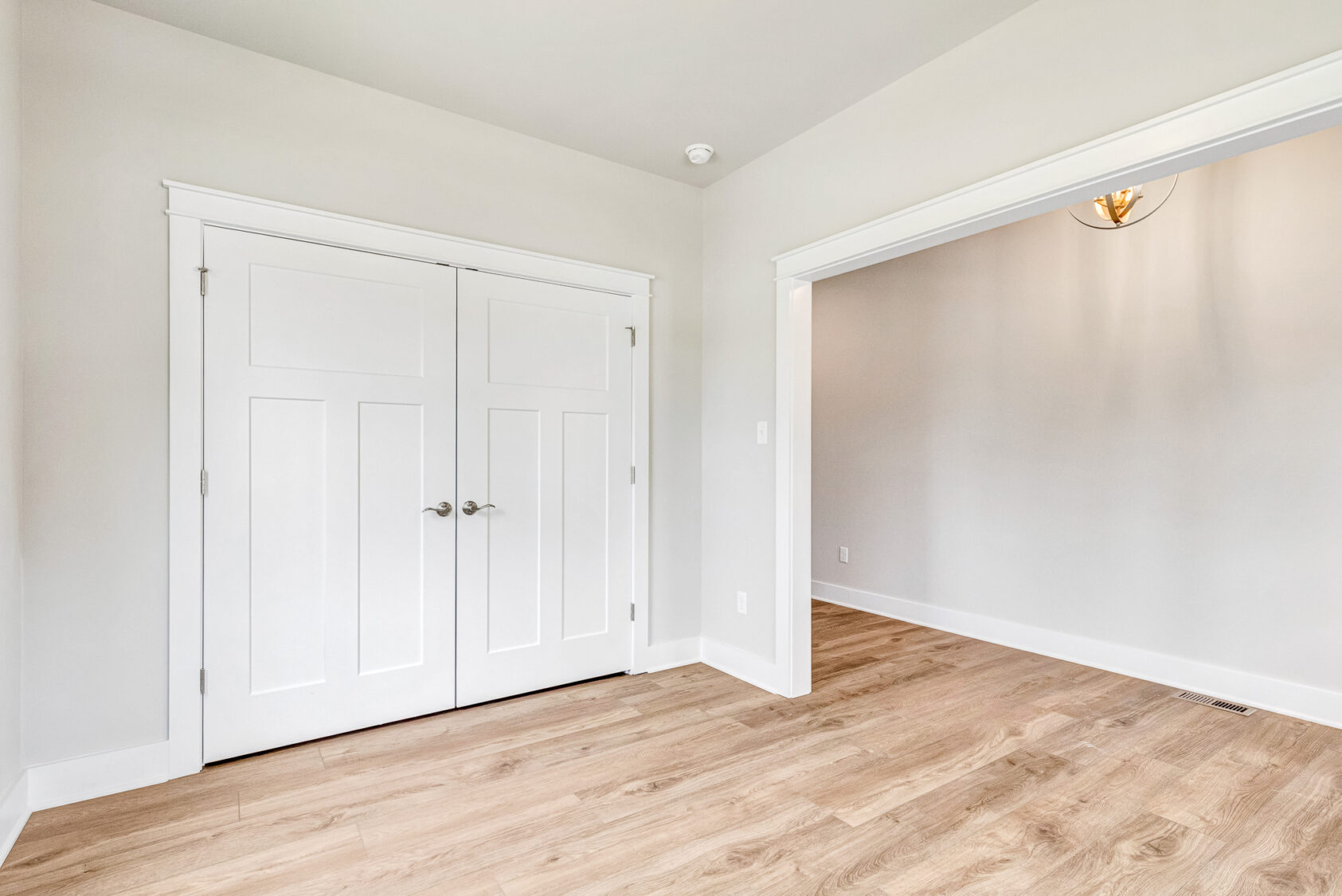 Empty room in Somerset Hill, Lot 20 with light wood flooring, white double doors, and light gray walls with white trim.