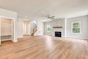 Bright living room in Somerset Hill with wood floors, white walls, fireplace, large windows, and ceiling fan.