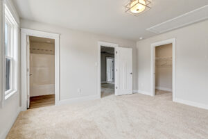 Bright, empty Somerset Hill bedroom with beige carpet, white walls, open closet, and access to Lot 20’s other rooms.