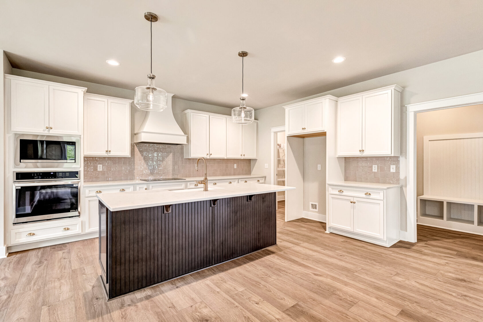 Modern kitchen in Somerset Hill with white cabinets, black island, wood floors, and built-in stainless appliances.