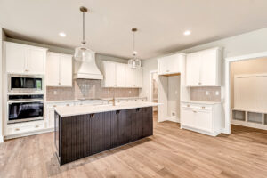 Modern kitchen in Somerset Hill with white cabinets, black island, wood floors, and built-in stainless appliances.
