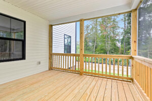 A covered wooden porch with railings on Somerset Hill, overlooking a grassy yard and trees in the background.