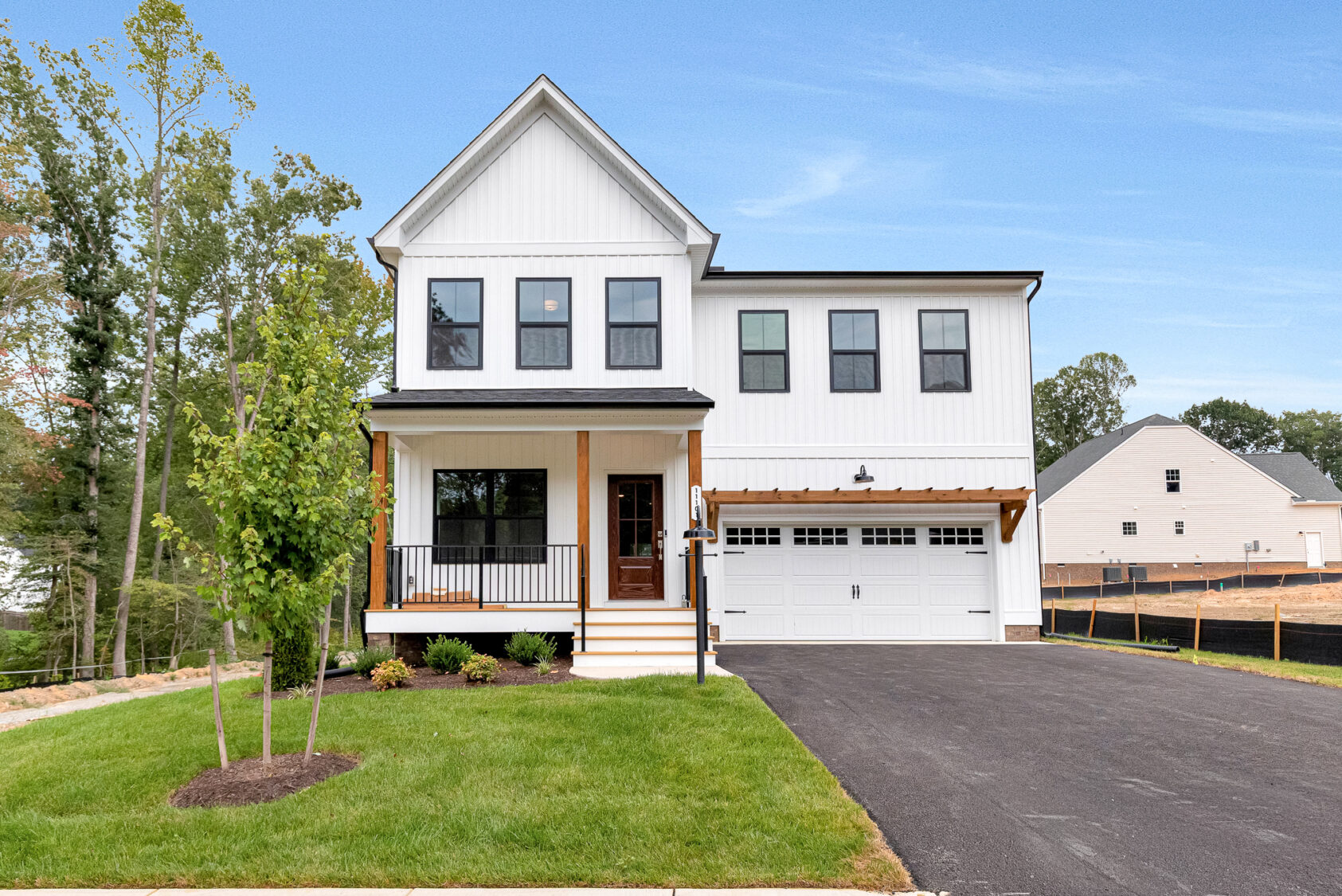 Modern white two-story house on Lot 20, Somerset Hill, with a porch, garage, driveway, and green lawn under a blue sky.