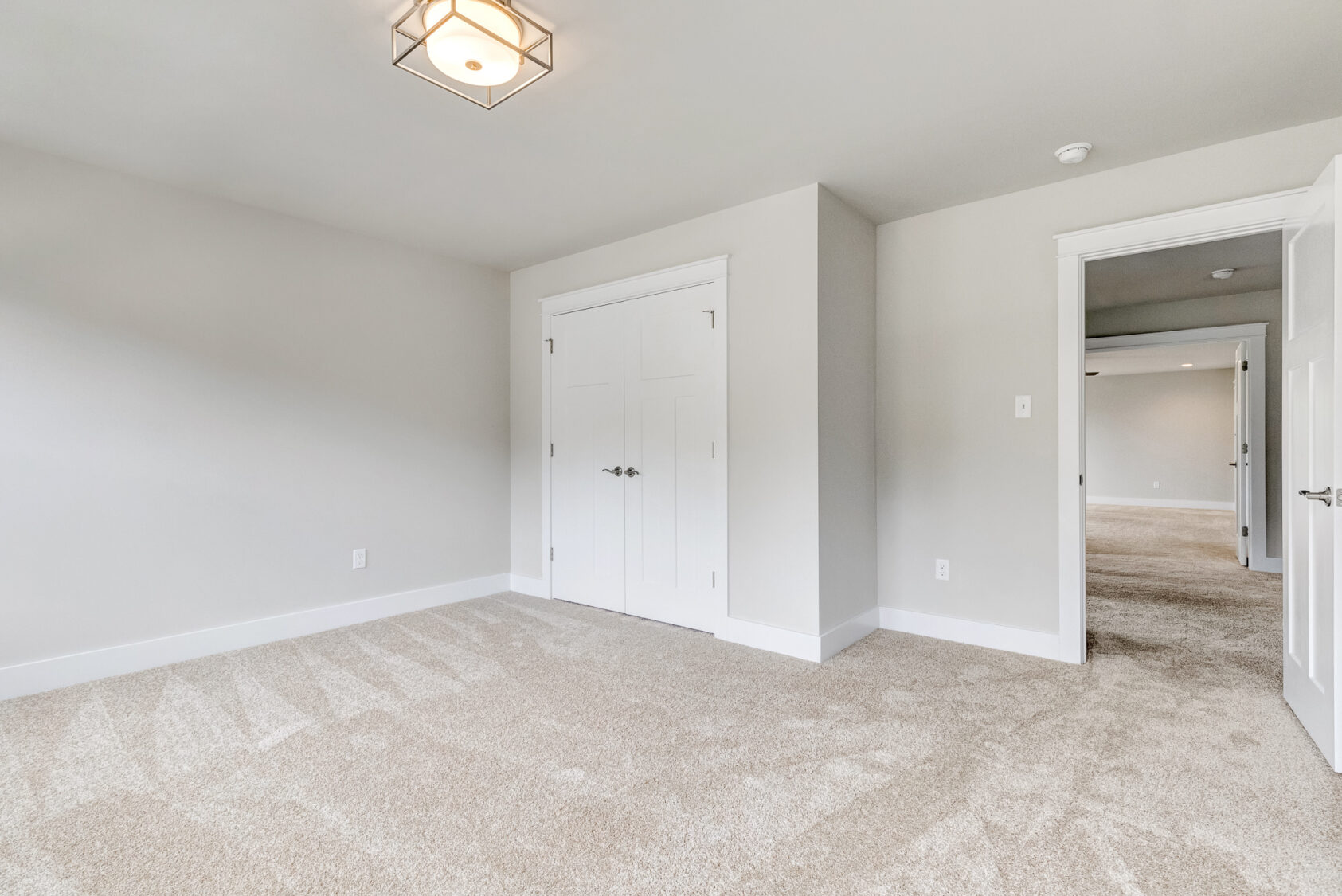 Empty beige carpeted bedroom on Lot 20, Somerset Hill, features double-door closet, white walls, and open hallway door.